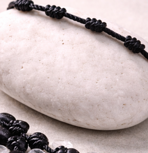 Pulsera 7 Nudos Negra sobre piedra blanca
