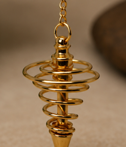Péndulo espiral de metal dorado con cadena plateada sobre fondo neutro.